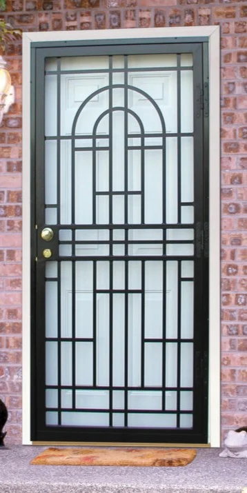 A black steel Home Guard security door with a bold geometric grille design is installed over a white entry door. The sturdy frame and dual lock hardware provide both strength and style, while the decorative pattern adds curb appeal against the brick home exterior.