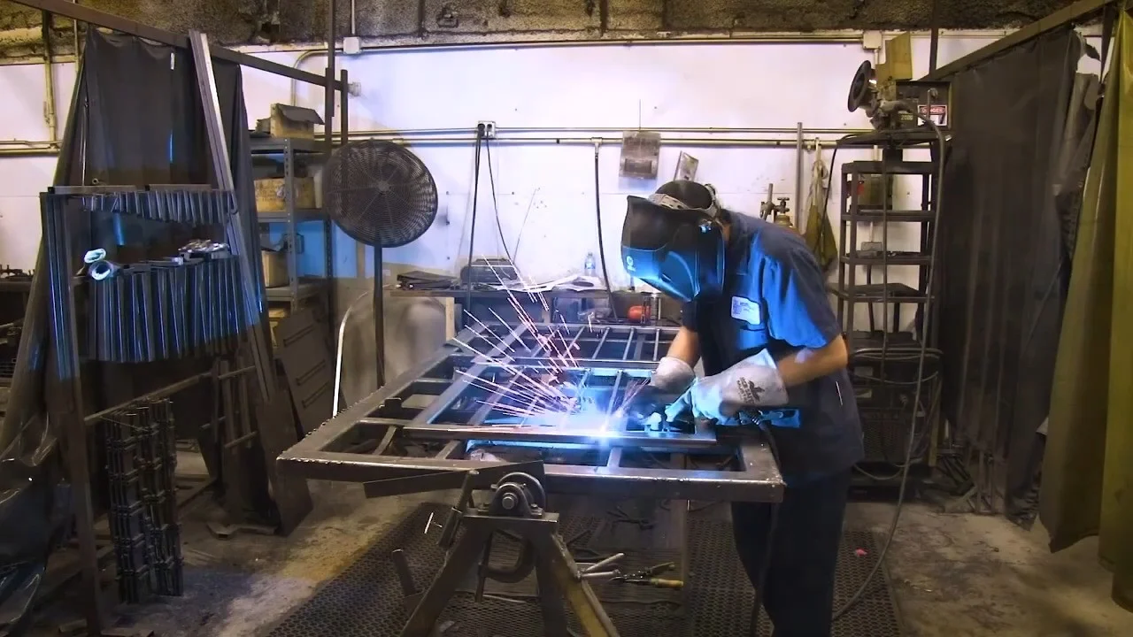 A Home Guard craftsman welds a steel security door frame inside the company’s manufacturing facility. Sparks fly as the worker, wearing protective gloves and a welding mask, reinforces the heavy-duty frame – showcasing the strength and precision built into every Home Guard security door.