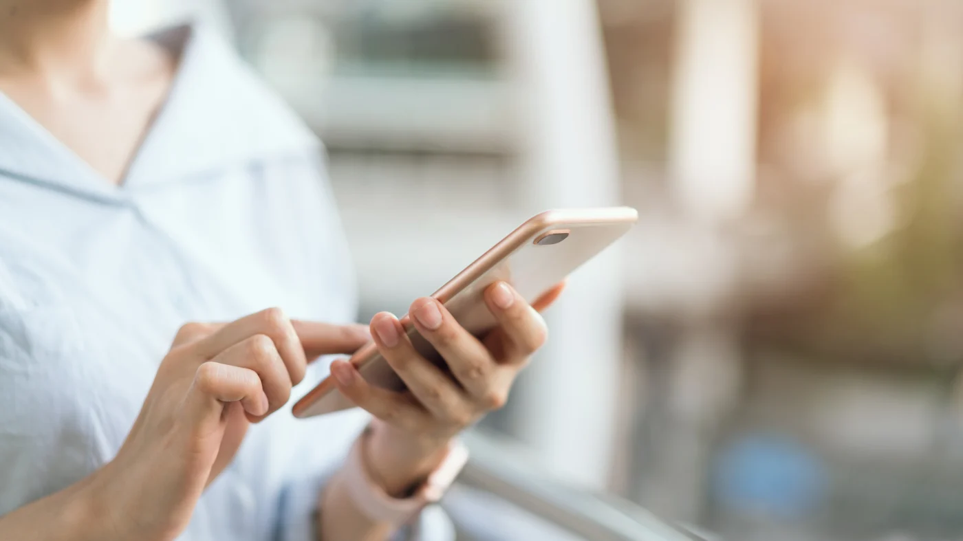 Close-up of a person using a smartphone, representing the first step of reaching out to schedule a window or entry door project.