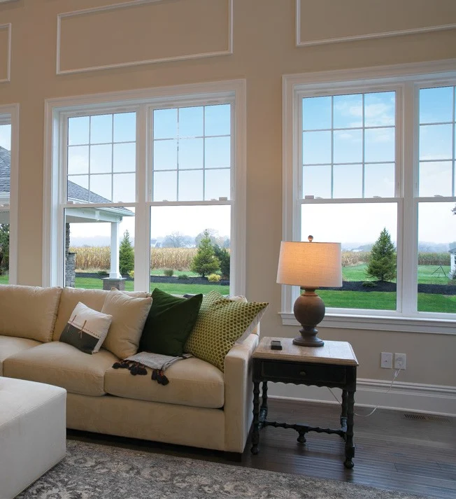 Three OKNA Eco-Pro 600 Series double-hung windows installed in a bright, inviting living room. The expansive glass panels and clean white frames deliver crisp views and fill the space with natural light. Designed for premium energy efficiency and lasting beauty, these windows blend elegant style with the performance today’s NY Metro homeowners expect.