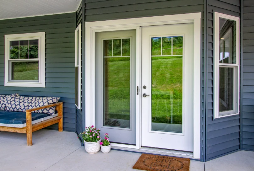 A sleek ProVia Legacy steel front door in a crisp white finish, paired with a full-glass panel and matching sidelites. Set against deep blue siding and framed with white trim, the entry exudes modern elegance and durability, ideal for NY Metro homes.