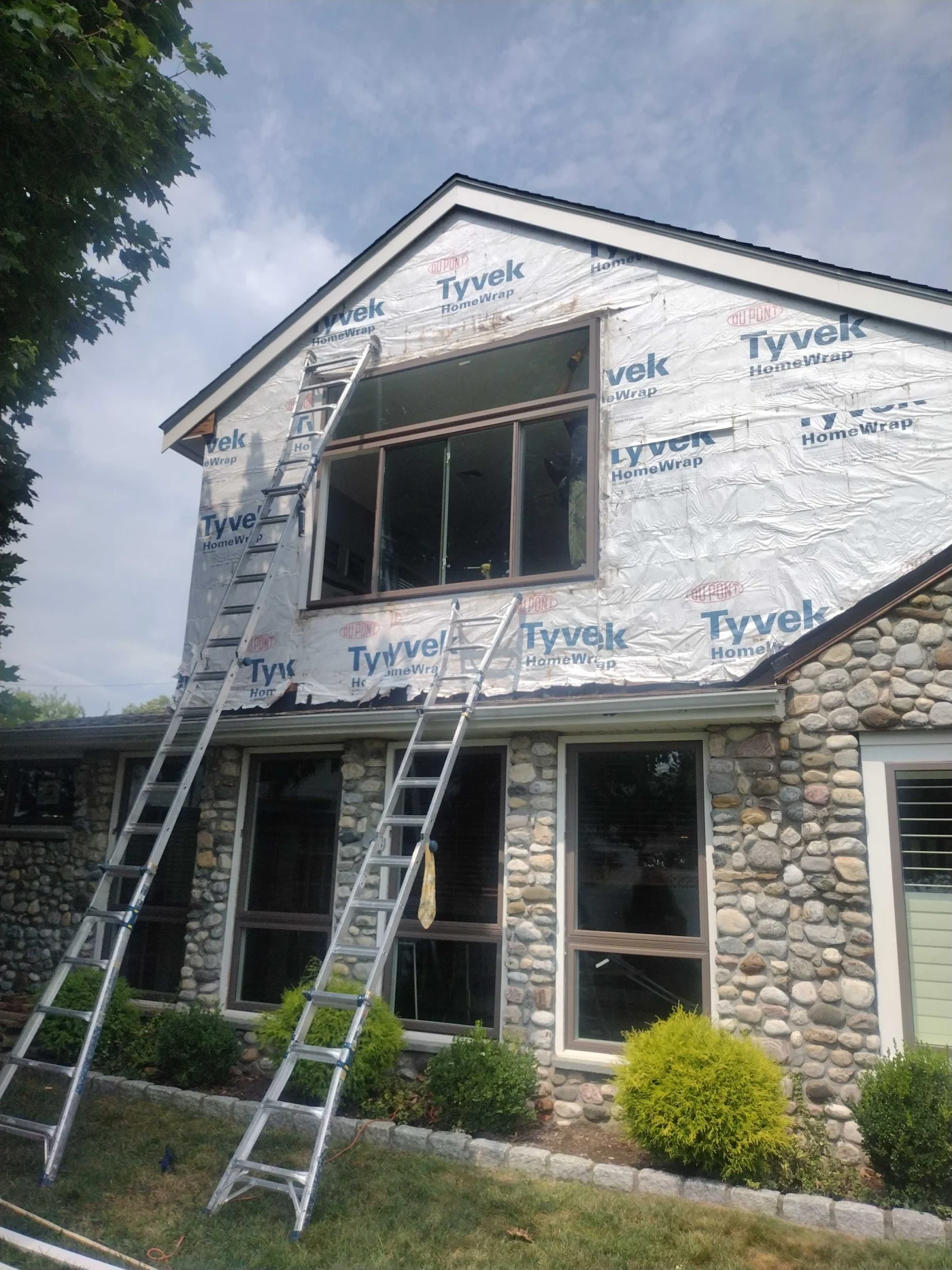 A two-story white siding home with black shutters and a dark front door, featuring newly installed energy-efficient windows on both floors