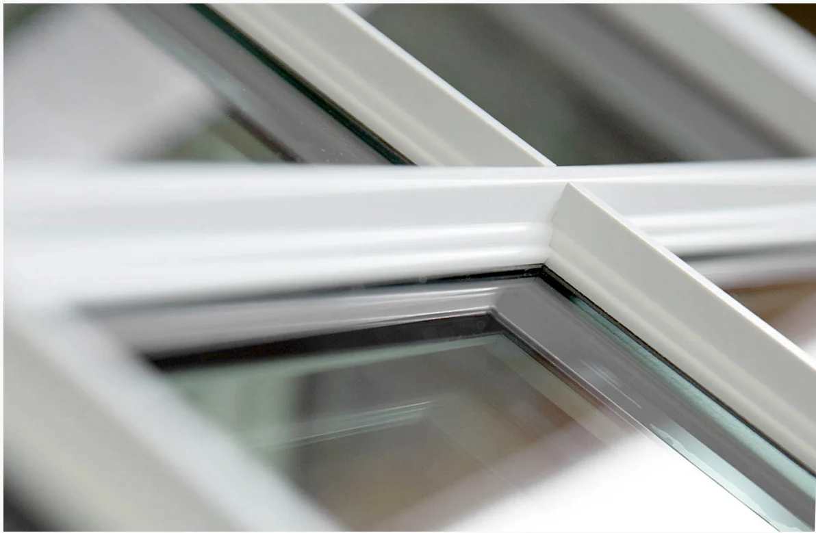 The refined craftsmanship of a Starmark Evo window. The white frame features clean, crisp lines and smooth contours that mimic the look of traditional millwork. The shot focuses on the intersection of the frame and grille, showing the precision joinery and snug fit around the insulated glass panes. The subtle reflection in the glass emphasizes clarity and quality, underscoring the window’s durability and premium finish.