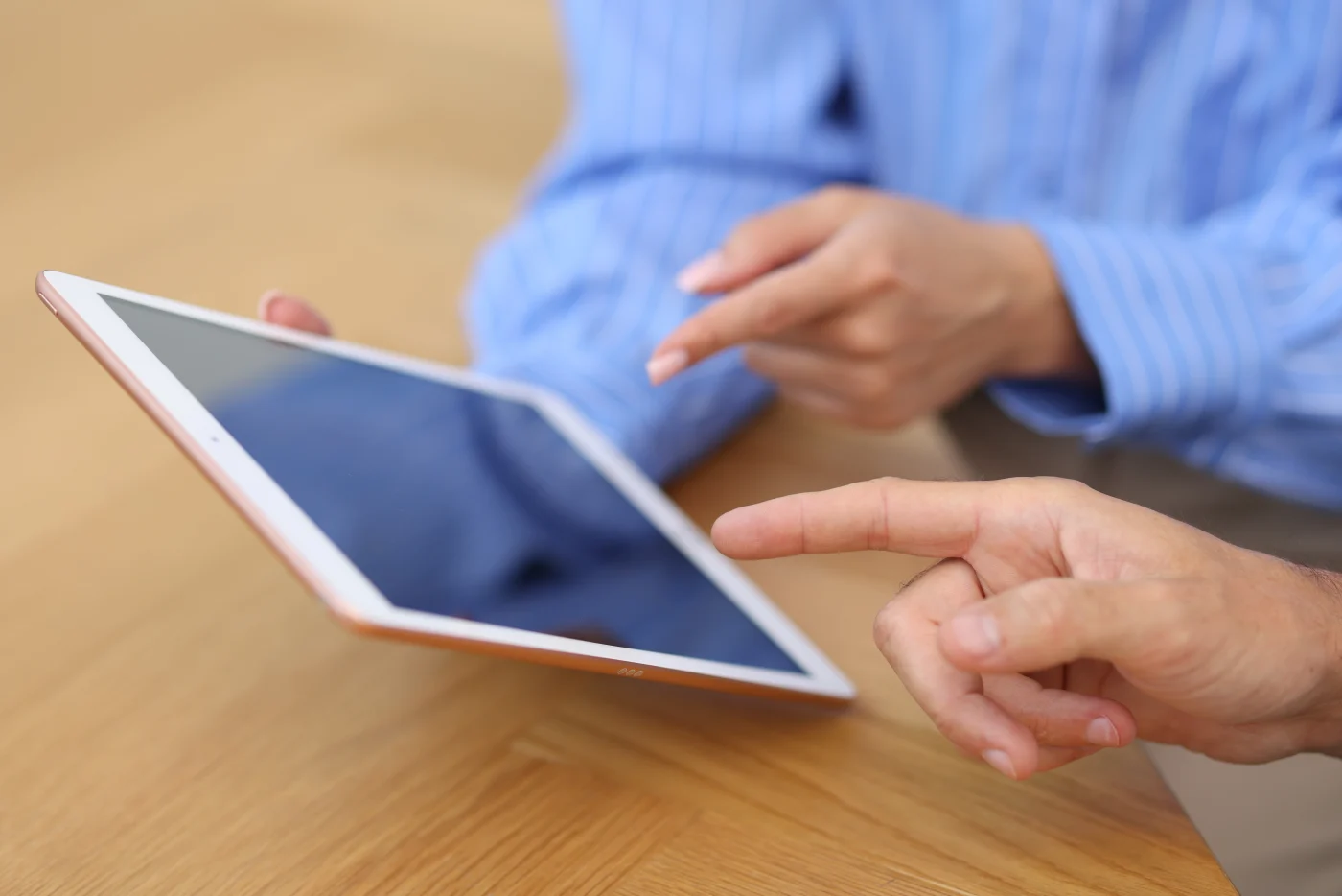 Close-up of two people reviewing a tablet together at a wooden table. The tablet represents the professional estimating software Window King uses to deliver accurate, honest quotes for window and entry door projects.