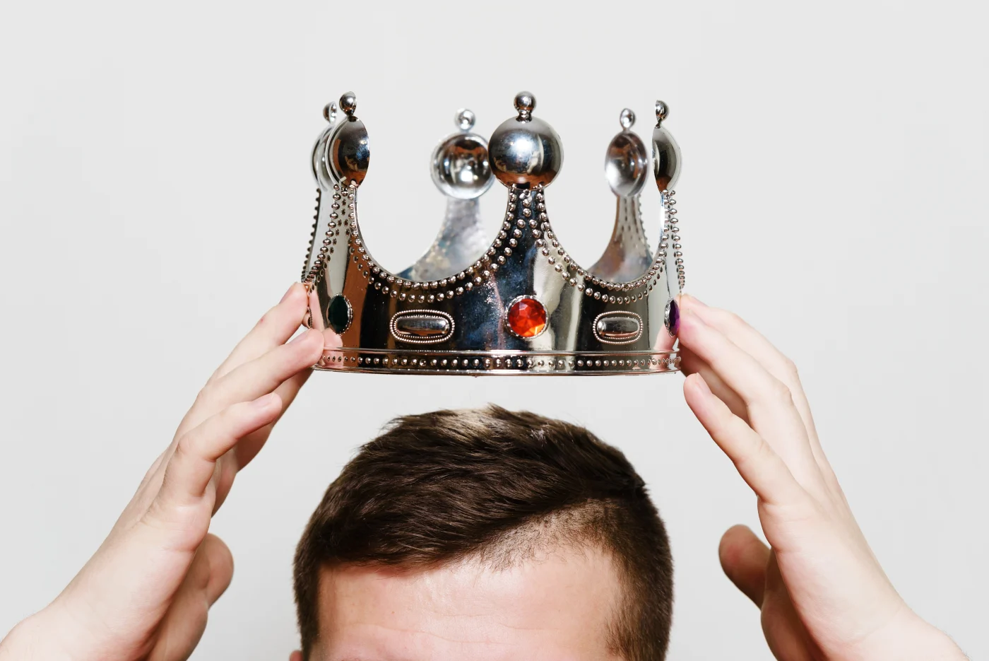 A close-up of a person placing a jeweled silver crown on their head, symbolizing the premium, respectful service customers receive with Window King’s “Royal Treatment.” The clean background and focus on the crown highlight the company’s high standards, warm professionalism, and pride in treating every customer like royalty—no gimmicks, just real respect.