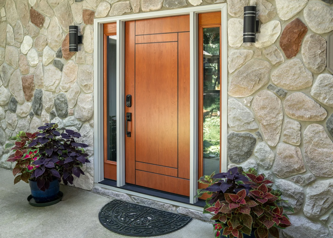 A ProVia steel entry door with sidelites, set against a natural stone exterior. The door’s rich cherry-toffee finish and clean, modern inlaid lines reflect both strength and elegance. With its heavy-duty construction and high-end appearance, it embodies the type of long-lasting, secure, and stylish product Window King installs for NY Metro homeowners who expect the best.
