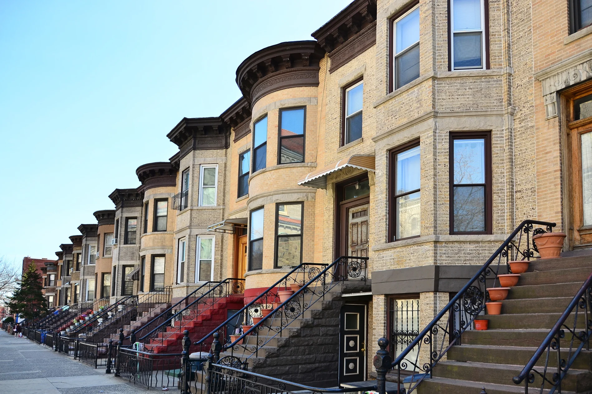 A row of classic Brooklyn, NY, brownstones with ornate facades, tall bay windows, and iron railings lining the stoops – a timeless reminder of the borough's character, craftsmanship, and neighborhood pride.