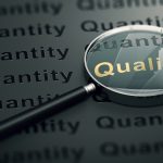 Close-up of a magnifying glass highlighting the word “Quality” in gold letters against a dark background filled with the repeated word “Quantity.