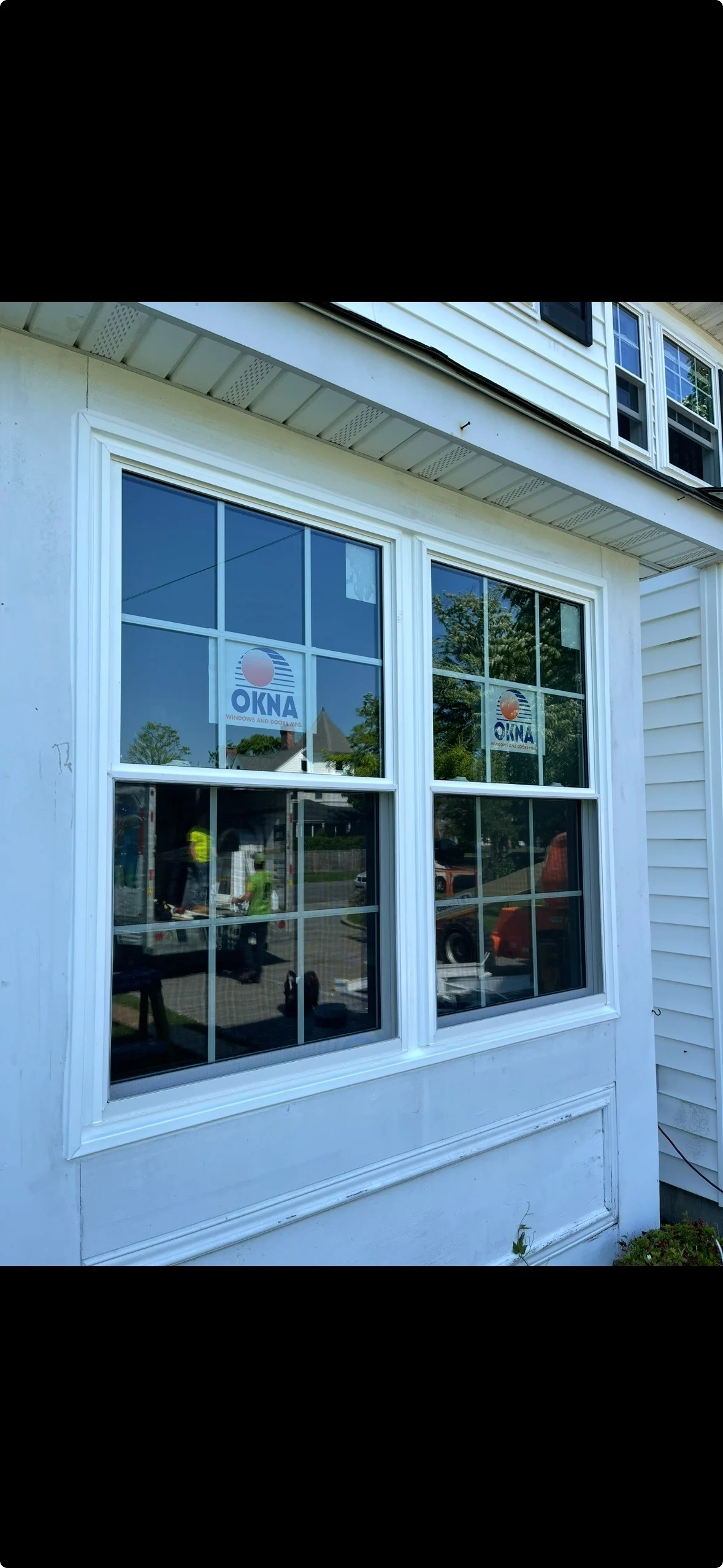 Double-hung replacement windows with decorative grids installed on a home exterior.