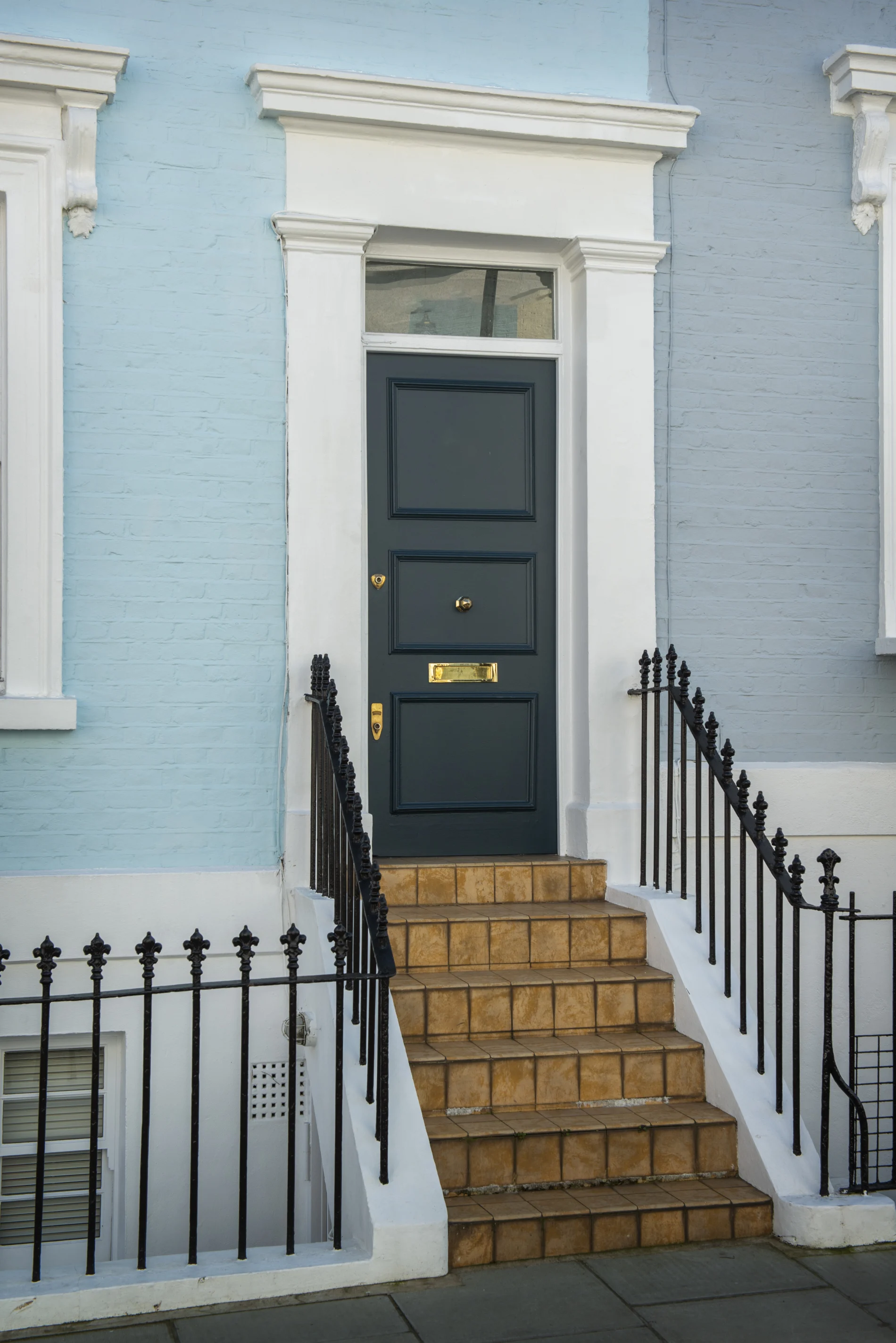 Elegant Brooklyn townhouse entry with bold purple front door, white brick façade, brass hardware, black iron railings, and classic city charm.