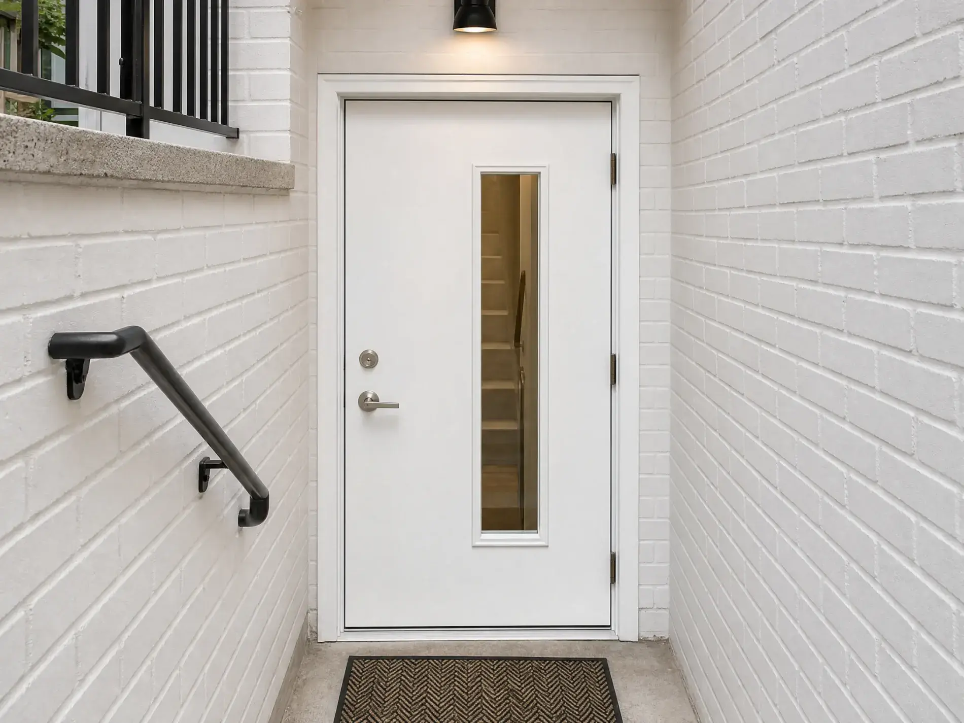 Amazing Door Installation In New Rochelle, NY | Window King White front entry door with two small windows and brass hardware set in brick beneath a red awning, beside a black mailbox and welcome mat