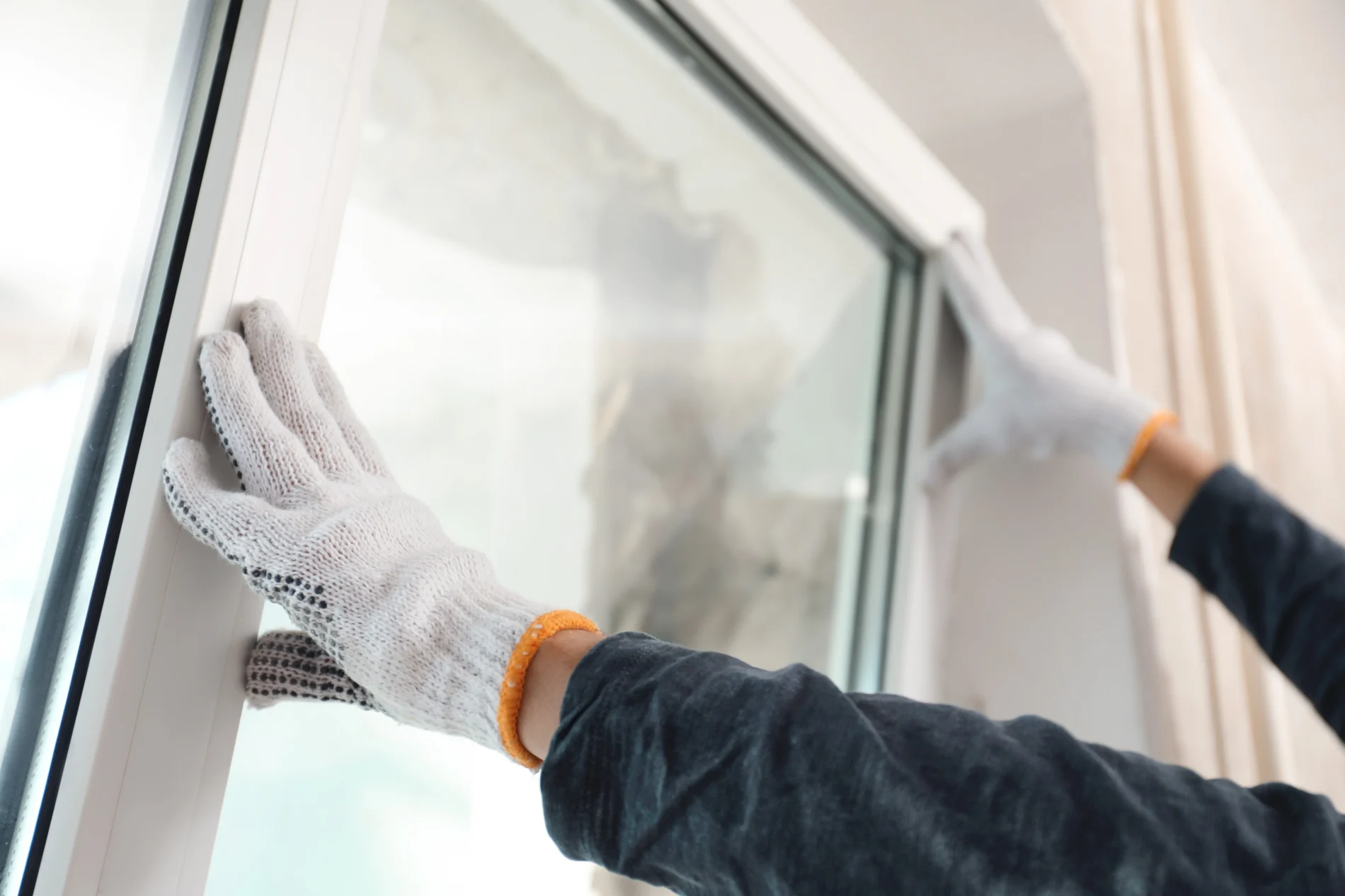 A close-up view of an installer working on a window replacement in a home.